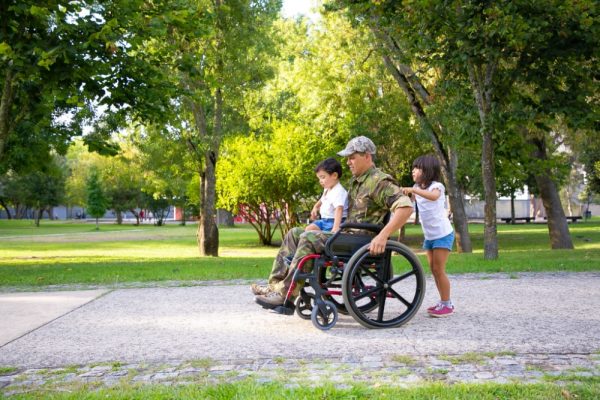 Article Banner - A male veteran in a wheelchair out in a park with his two children